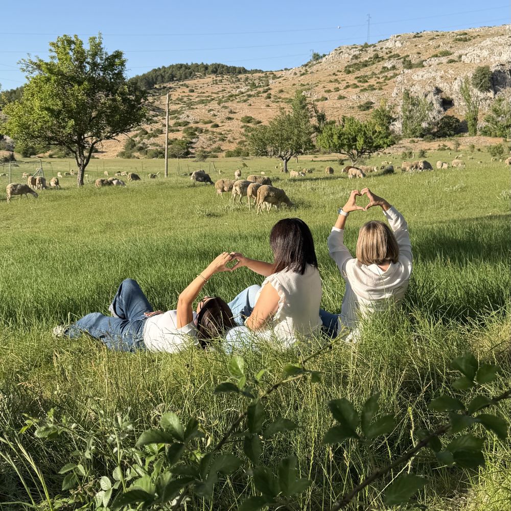 Mari Carmen, Ana Belén y Paqui, las tres hermanas fundadoras de D'Arome, formando corazones con las manos mirando los campos de Pontones (Sierra de Segura, Jaén), su pueblo natal y origen del aroma Nuevos Comienzos de LoeS – D'Arome