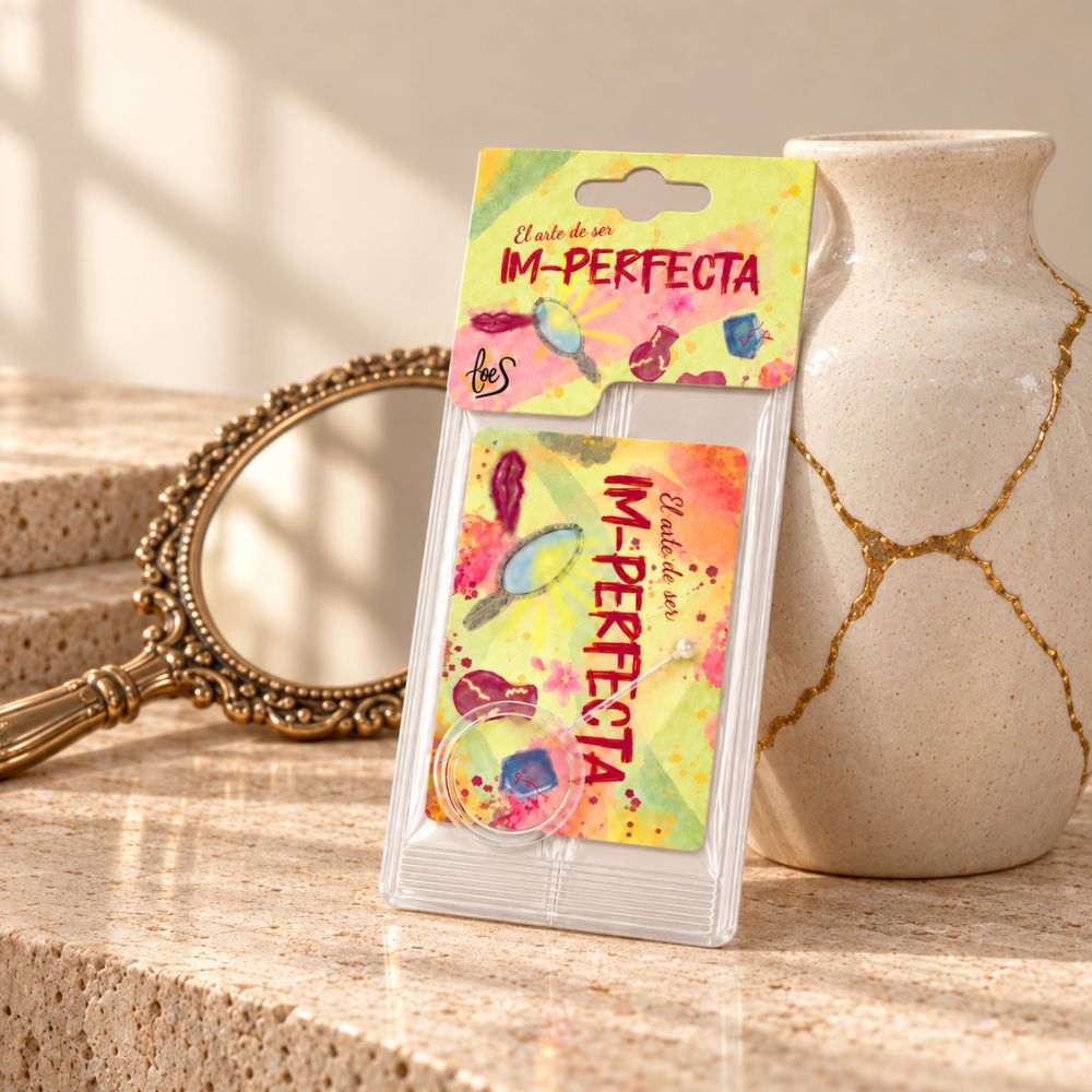 Ambientador de coche Im-Perfecta de LoeS en su blíster, apoyado junto a un jarrón restaurado con kintsugi y un espejo de mano dorado – D'Arome