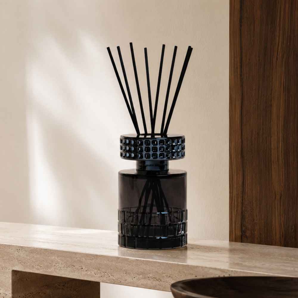 Ambientador Mikado CelebrationMaison Berger en cristal negro con capuchón calado sobre repisa de mármol – D'Arome