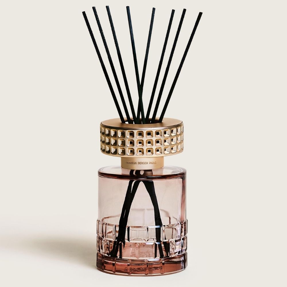 Vista frontal del ambientador mikado Celebration Nude Maison Berger con frasco rosa empolvado tallado, embellecedor dorado y varillas de fibra negras – D'Arome