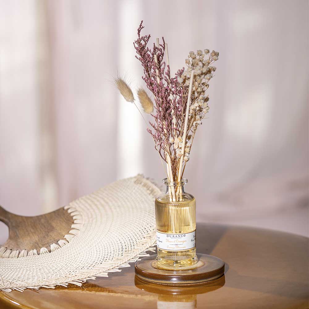 Difusor de aromas Flor de Azahar de Durance con ramo de flores secas en un estilo decorativo natural, sobre una mesa junto a un abanico.