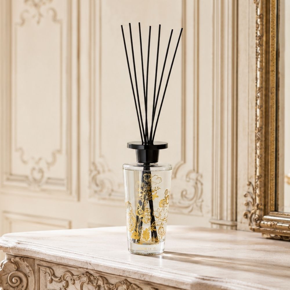 Detalle del ambientador mikado Trésor de Fleurs Marquise Mathilde M con frasco de cristal floral dorado sobre recibidor de mármol – D'Arome