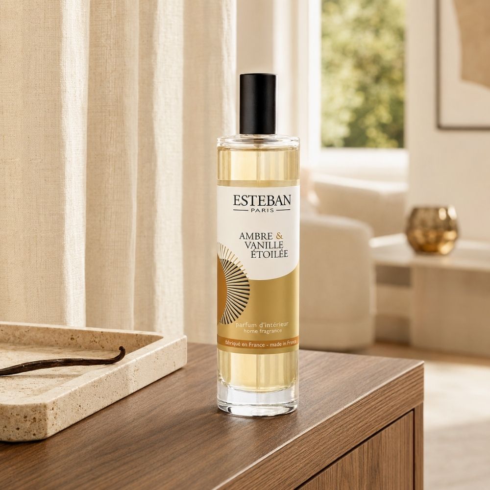 Ambientador spray Ambre et Vanille Étoilée Esteban París de 75 ml sobre mueble de salón junto a una vaina de vainilla – D'Arome