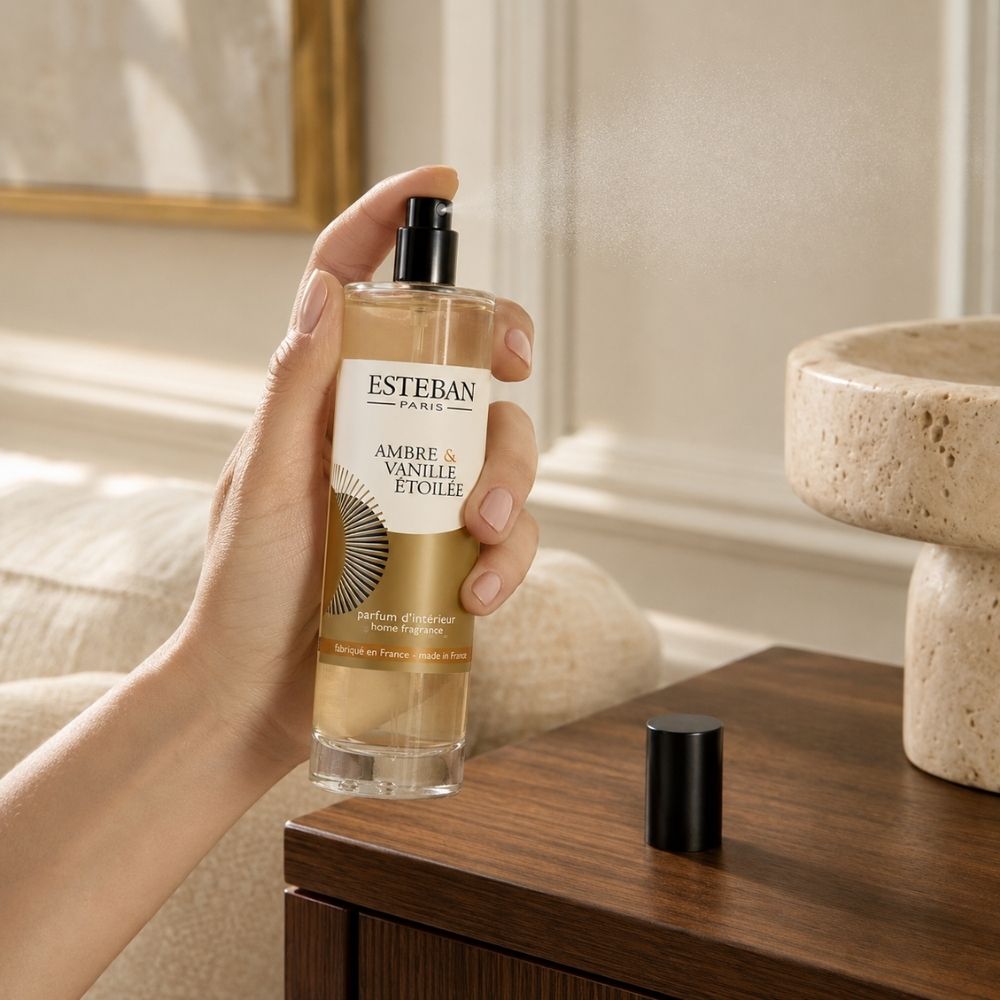 Mujer pulverizando el ambientador spray Ambre et Vanille Étoilée Esteban París para perfumar la estancia – D'Arome