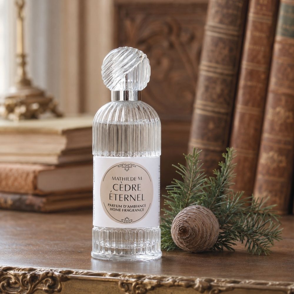 Ambientador spray Cèdre Éternel 100ml de Mathilde M con tapón facetado sobre mesa de biblioteca antigua – D'Arome