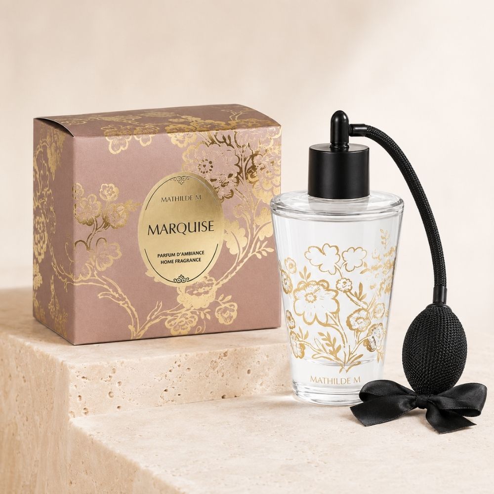 Ambientador spray de vaporizador de pera colección Trésor de Fleurs Marquise de Mathilde M con estampado floral dorado junto a su caja rosa sobre travertino – D'Arome