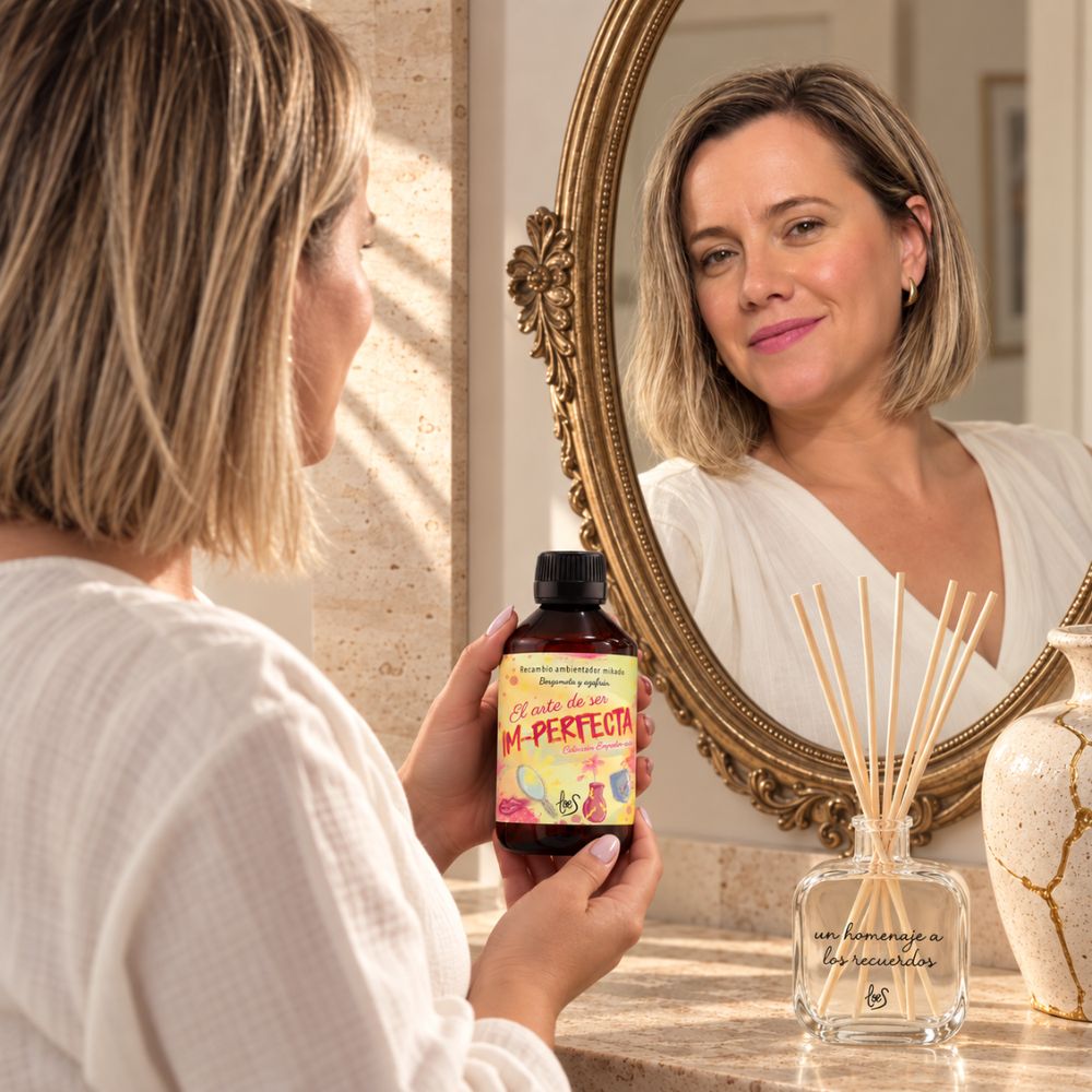 Ana Belén fundadora de D'Arome, mirándose al espejo con el recambio mikado Im-Perfecta de LoeS en la mano – D'Arome