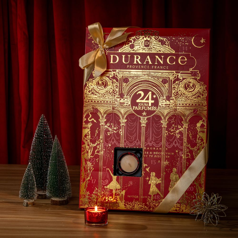 Calendario de adviento Durance 2026 abierto mostrando una vela perfumada encendida en su portavelas rojo granate, colección Ópera de Aviñón – D'Arome