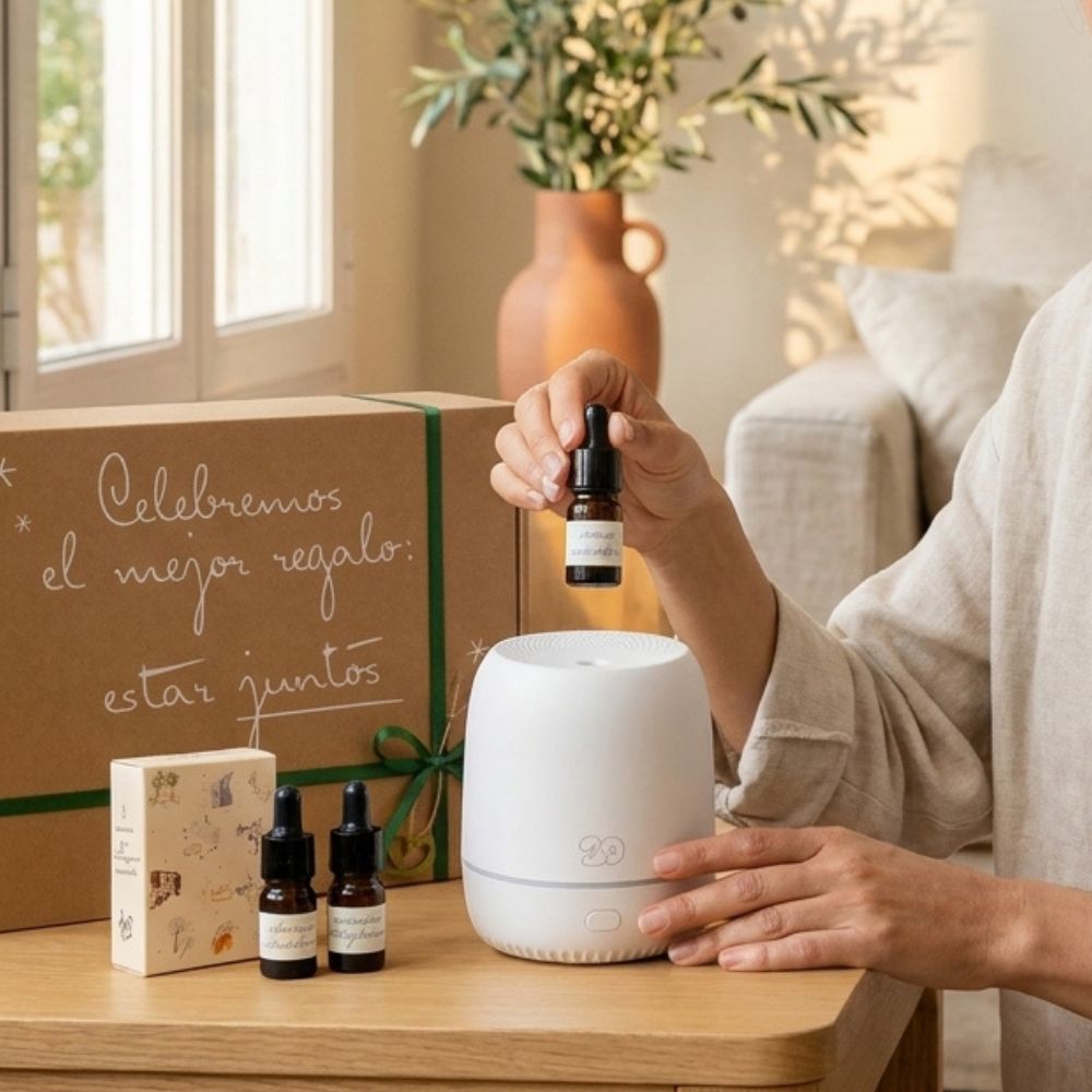 Paso a paso del difusor Sira del cofre regalo original de D'Arome: vertiendo mini esencia LoeS en el depósito abierto del difusor blanco junto a cajita de aromas y caja kraft – D'Arome