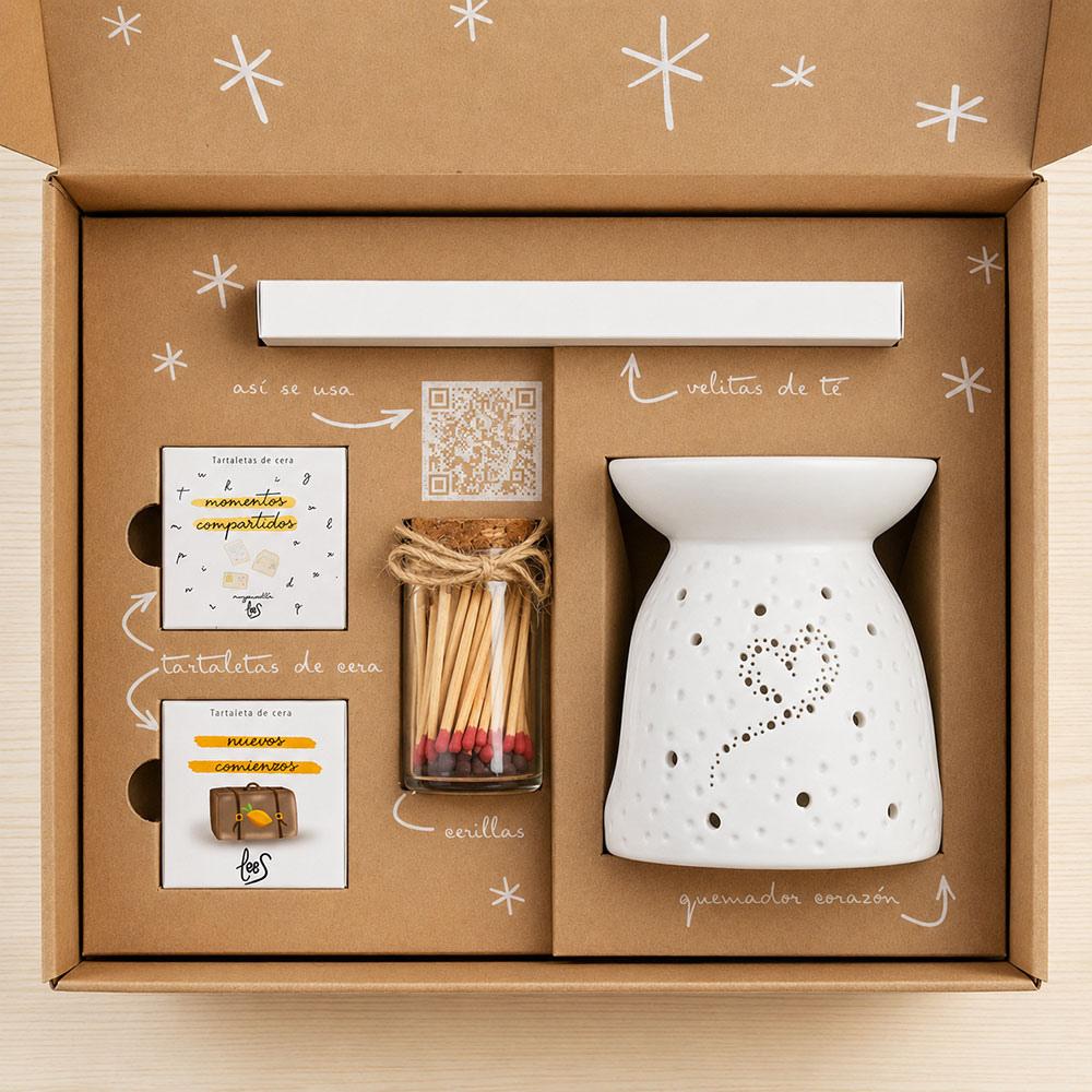 Vista cenital del interior del cofre regalo para profesora de D'Arome con quemador corazón, tartaletas de cera Momentos Compartidos y Nuevos Comienzos de LoeS, frasquito de cerillas decorativas y código QR de instrucciones – D'Arome
