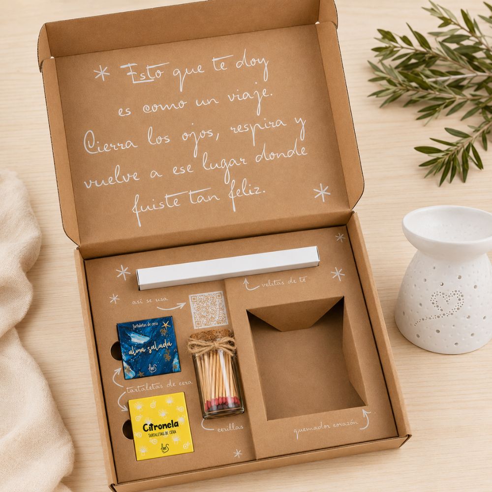 Cofre regalo de verano LoeS abierto sobre mesa de madera con quemador de cerámica corazón al lado y rama de olivo, ambiente mediterráneo – D'Arome