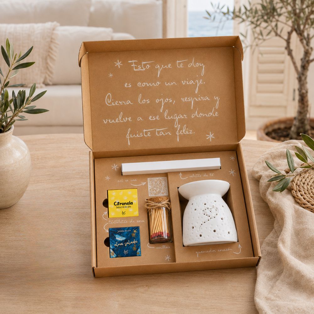 Cofre regalo de verano "Huele a vacaciones" de LoeS abierto sobre mesa de salón con vistas al mar y olivo, set ideal para regalar este verano – D'Arome