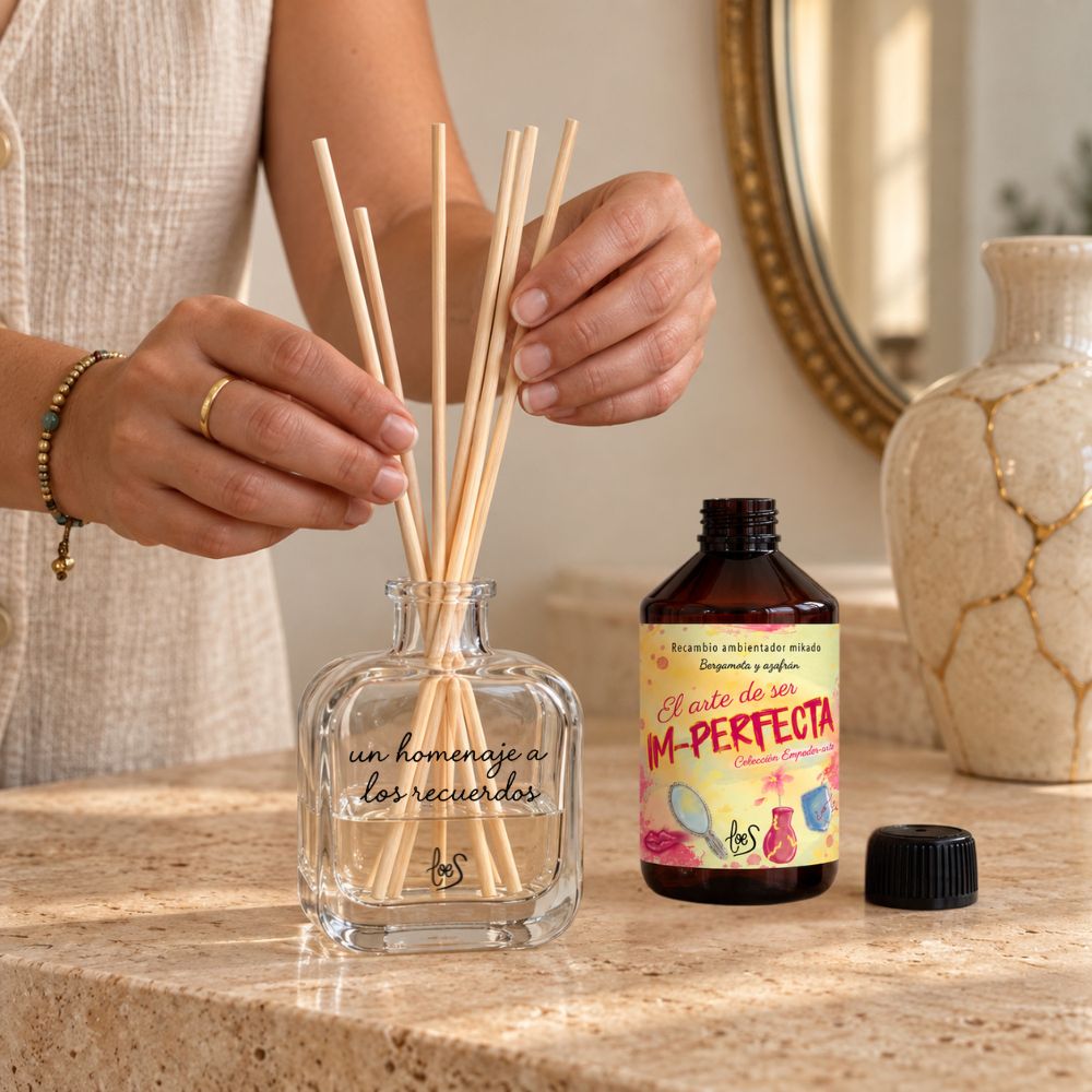 Manos mujer colocando las varillas naturales en el frasco 'Un homenaje a los recuerdos' recién rellenado con Im-Perfecta de LoeS – D'Arome