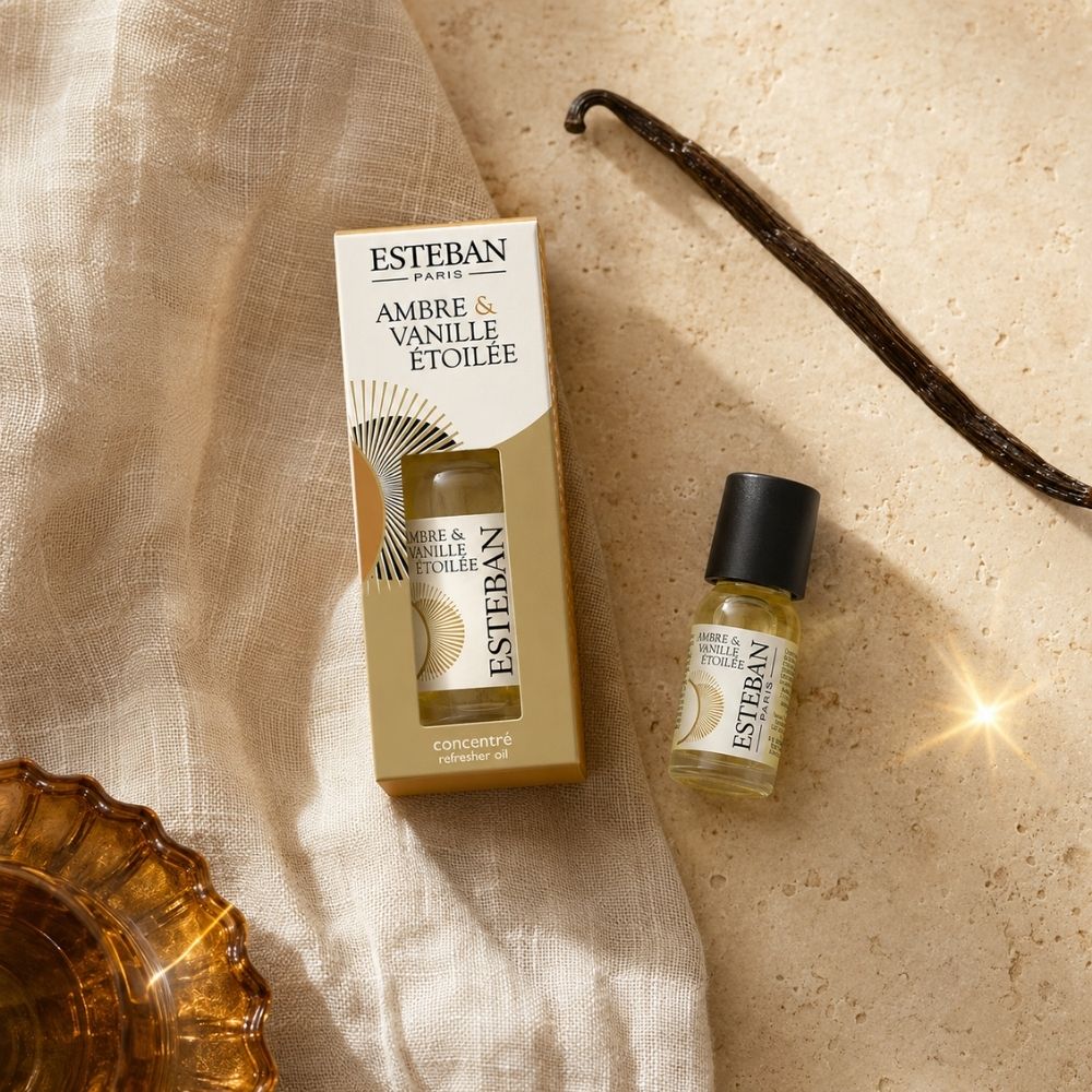 Detalle del concentrado de perfume Ambre et Vanille Étoilée Esteban París con vaina de vainilla sobre superficie de piedra – D'Arome