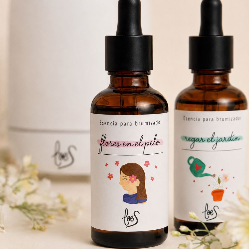 Detalle de las esencias para brumizador LoeS Flores en el Pelo y Regar el Jardín con etiquetas ilustradas y brumizador cerámico al fondo – D'Arome