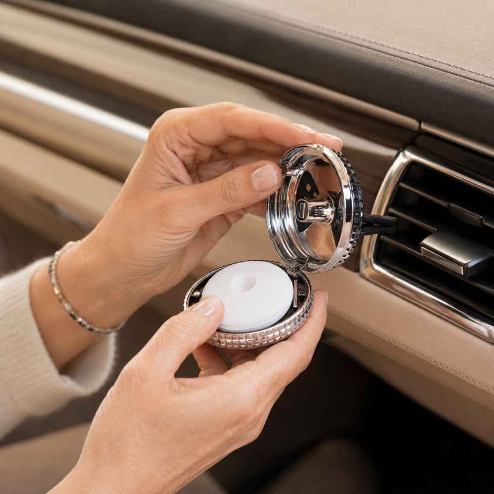 Detalle de manos abriendo el difusor de coche plateado Maison Berger para cambiar la recarga perfumada – D'Arome