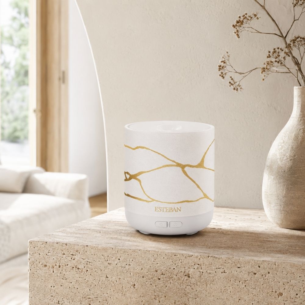 Difusor de bruma de perfume Easy Living White & Gold Esteban París con estampado dorado kintsugi sobre mueble de travertino – D'Arome