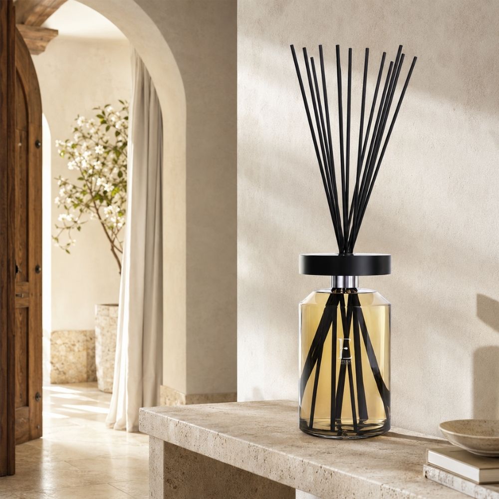 Difusor mikado Ellipse Édition Premium Néroli de Esteban Paris con líquido dorado, junto a un arco de piedra y un naranjo en flor – D'Arome