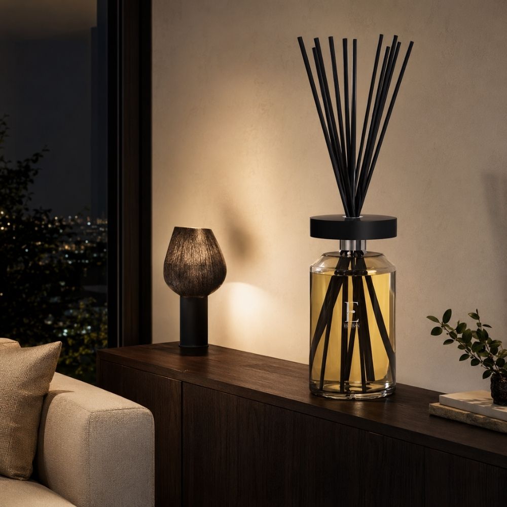 Difusor Ellipse Néroli de Esteban Paris sobre mueble oscuro en un salón de noche, con lámpara de cerámica encendida y vistas a la ciudad – D'Arome