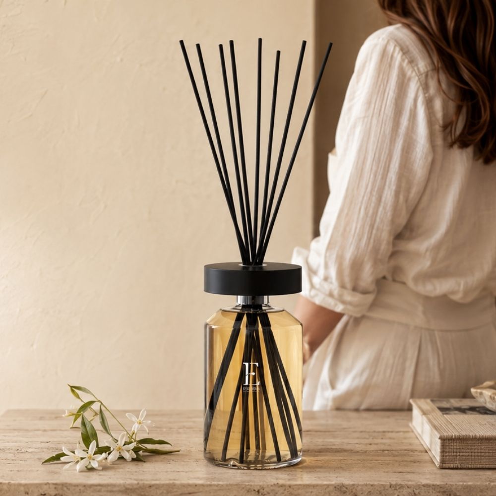 Difusor Ellipse Néroli de Esteban Paris sobre mesa de madera con flores de azahar, junto a una mujer con camisa de lino en segundo plano – D'Arome