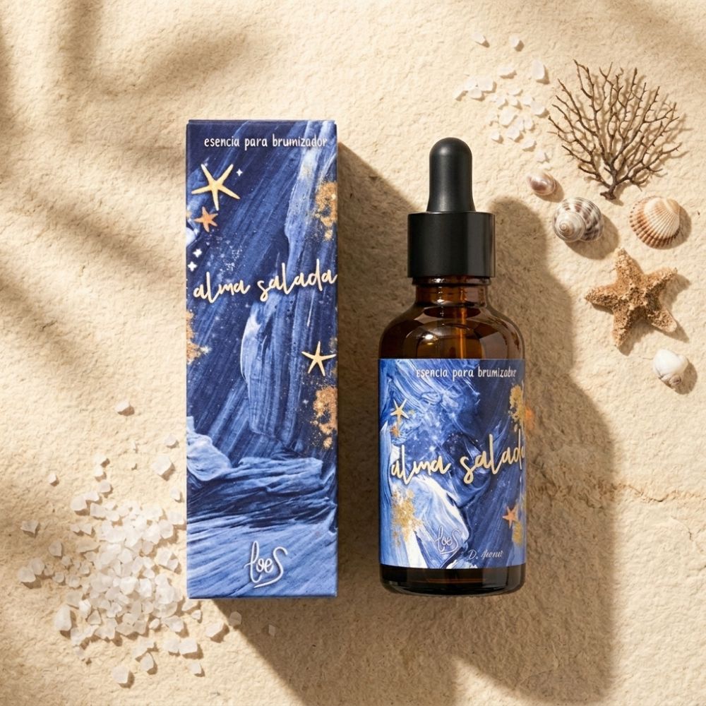 Esencia para brumizador Alma Salada de LoeS con caja azul y estrellas doradas sobre arena de playa junto a conchas, estrella de mar, coral y cristales de sal marina – D'Arome