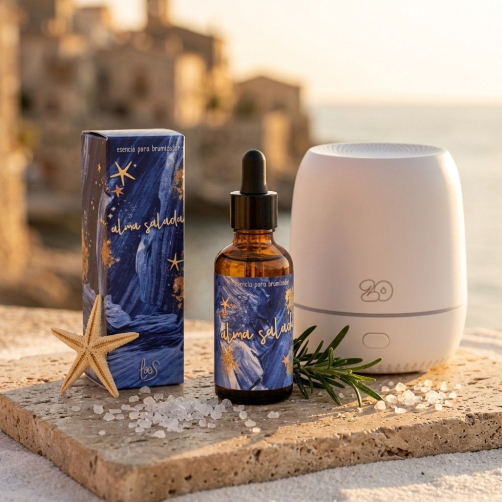 Esencia para brumizador Alma Salada de LoeS con caja azul, difusor Sira blanco, estrella de mar, romero y cristales de sal marina al atardecer con pueblo costero mediterráneo de fondo – D'Arome
