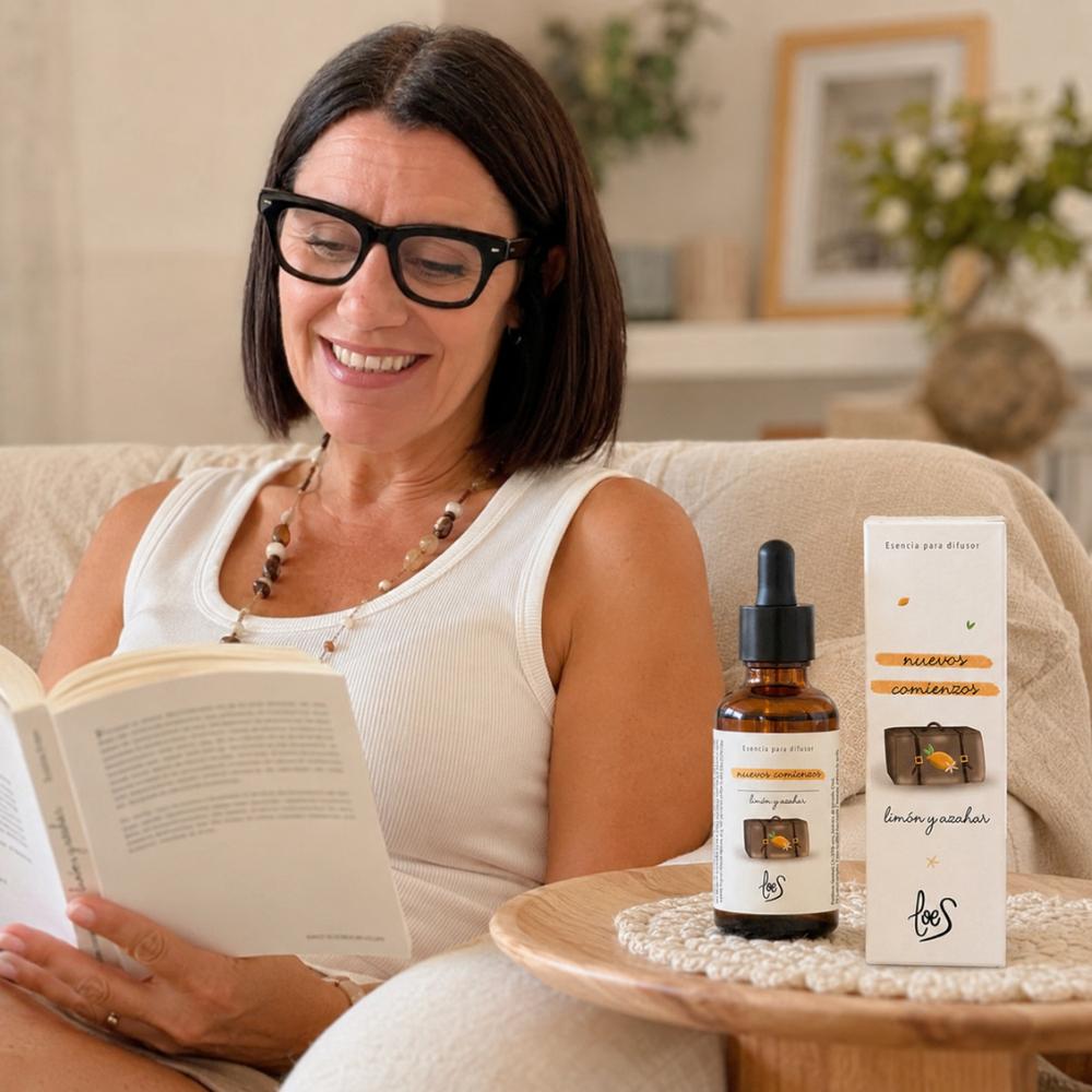 Mari Carmen, CEO y experta en aromas de D'Arome, leyendo en sillón con esencia para difusor Nuevos Comienzos LoeS limón y azahar en mesita