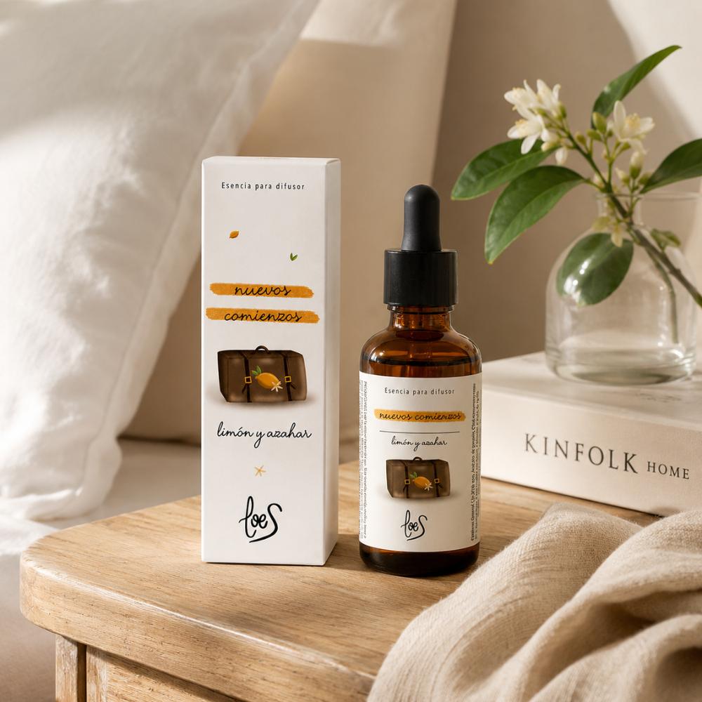 Esencia para difusor Nuevos Comienzos LoeS limón y azahar con caja sobre mesita de madera nórdica con flor de azahar y libro Kinfolk – D'Arome