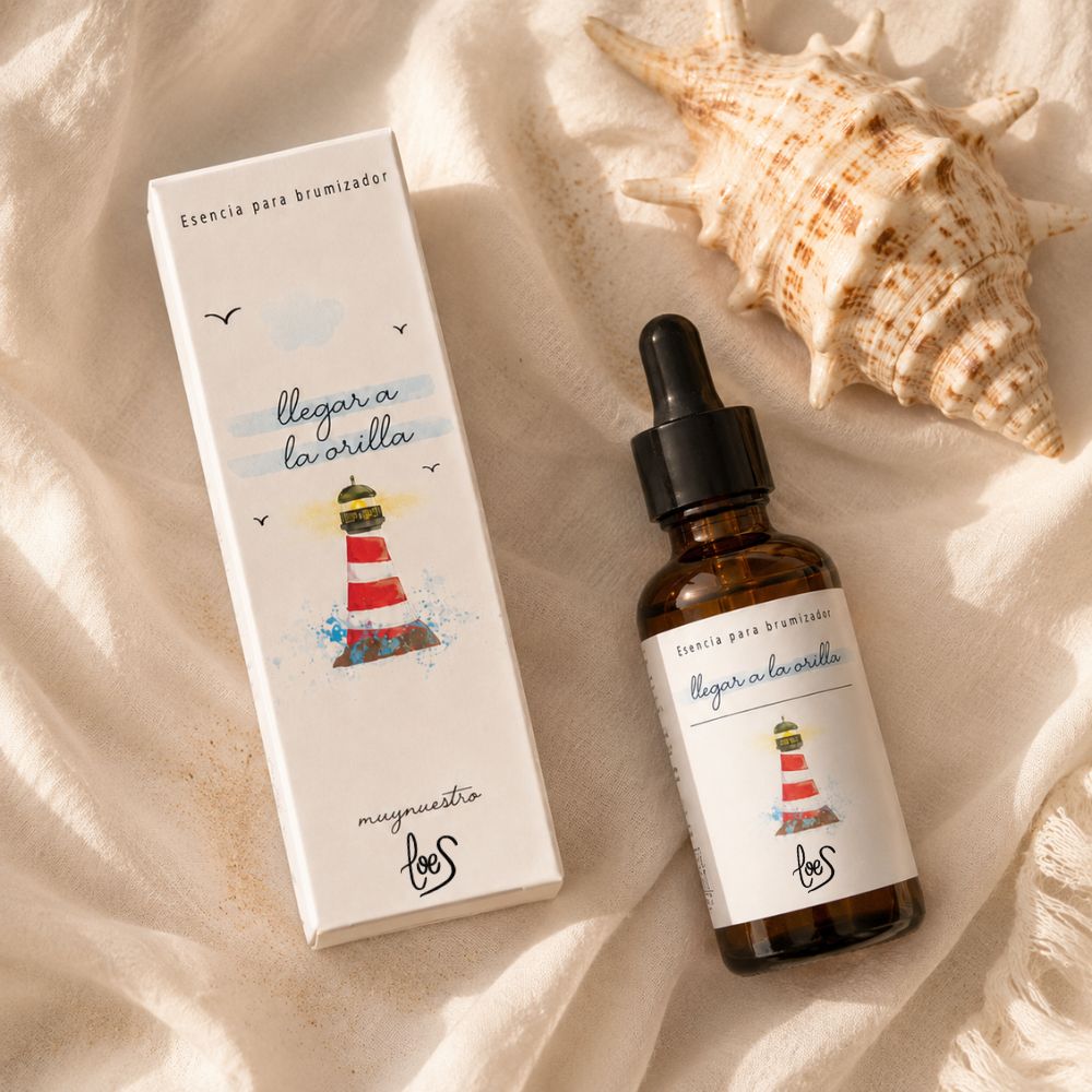 Flatlay de la esencia para difusor de aromas "Llegar a la orilla" de LoeS junto a una concha caracola sobre lino blanco con arena, conexión con el aroma marino del producto – D'Arome