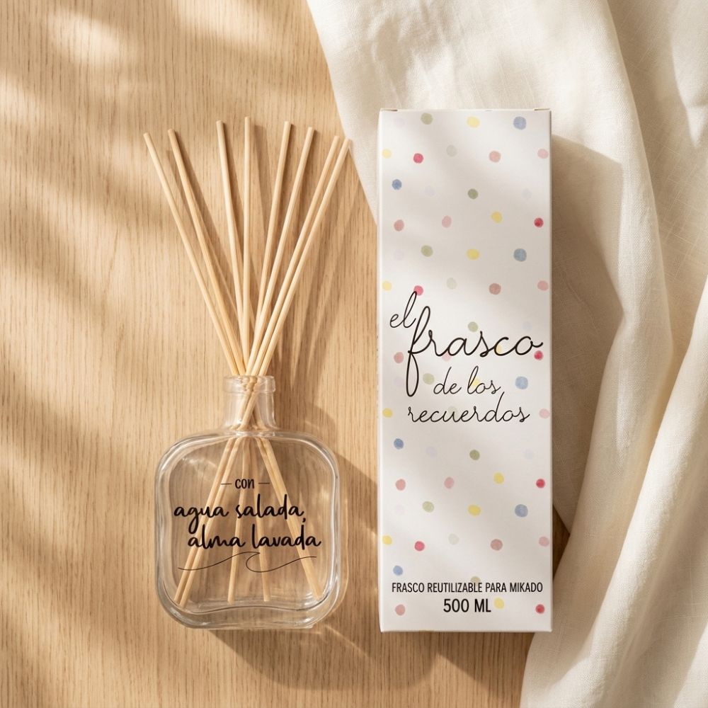 Frasco mikado vacío de cristal con varillas de ratán junto a su caja decorativa de lunares de colores, modelo Agua Salada Alma Lavada de LoeS 500ml sobre mesa de madera – D'Arome
