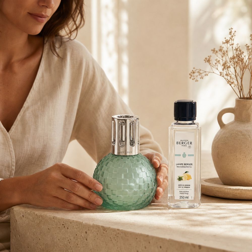 Lámpara catalítica Disco Verde Escarchada Maison Berger colección Estivale en cocina mediterránea sobre base de piedra una mujer mostrandola