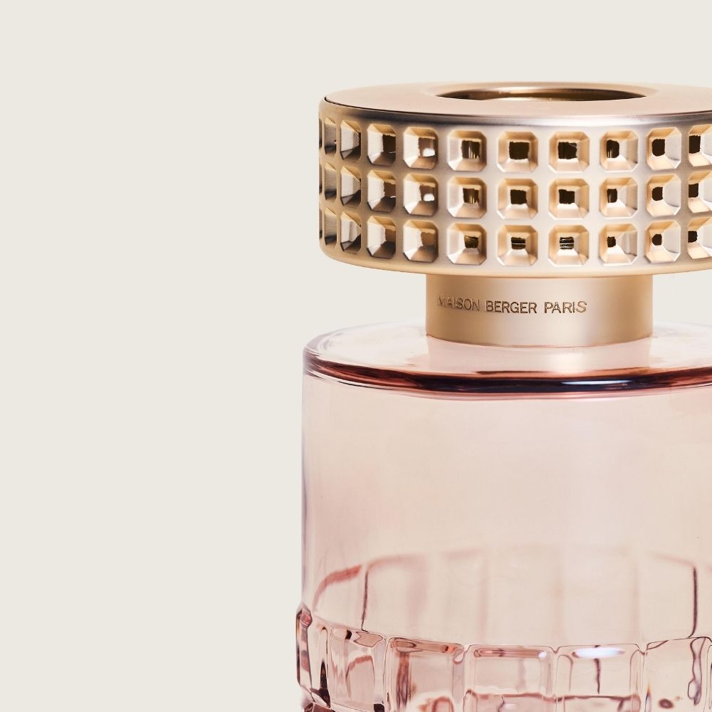 Detalle de la tapón embellecedor doradaofacetada tipo piedras engastadas de la lámpara catalítica Celebration Nude Maison Berger sobre cristal rosa – D'Arome