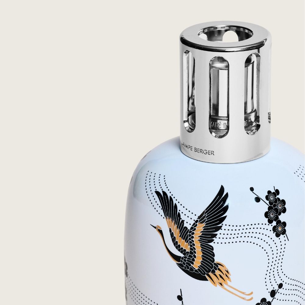 Detalle de la montura plateada de la lámpara catalítica Sakura Blanca Maison Berger con grabado Lampe Berger y grulla ilustrada sobre cerámica blanca – D'Arome