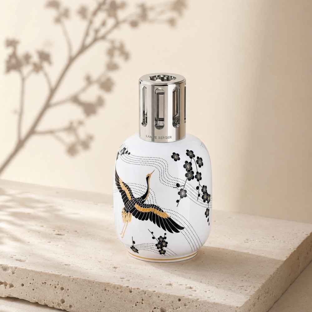 Lámpara catalítica Sakura blanca con de Maison Berger con grulla dorada y flores de cerezo sobre bloque de piedra travertino – D'Arome