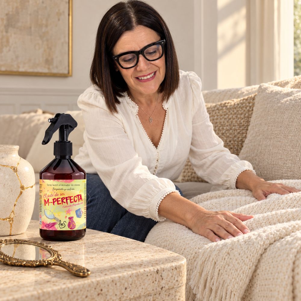Mari Carmen, CEO y fundadora de D'Arome, refrescando una manta de punto en el sofá con el spray textil Im-Perfecta de LoeS – D'Arome