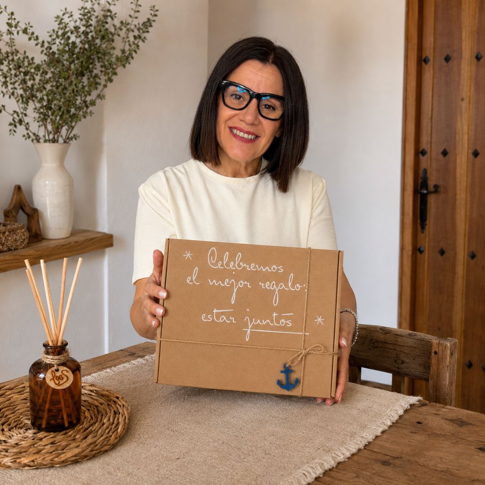 Mari Carmen, CEO y experta en aromas de D'Arome, presentando el cofre regalo de verano mikado Alma Salada de LoeS con frasco recargado al fondo, ambiente recibidor mediterráneo – D'Arome