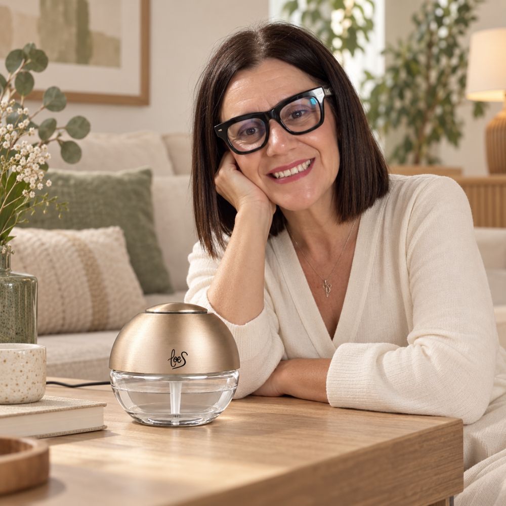 Mari Carmen sonriendo junto a la Bola de Olor dorada LoeS sobre mesa de salón, ambientador antiolores – D'Arome
