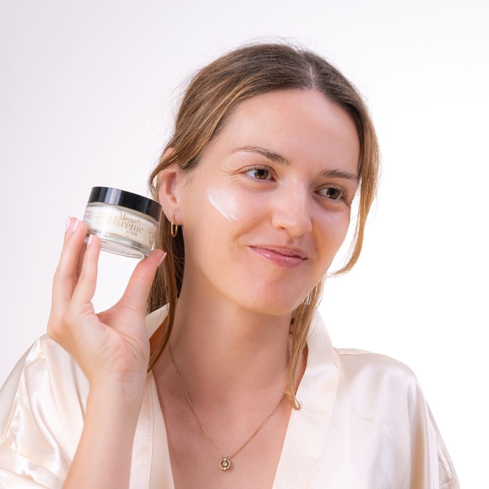 Mascarilla crema de noche Colección Serenidad de Durance aplicada en la mejilla, sosteniendo el frasco a la altura del rostro – D'Arome