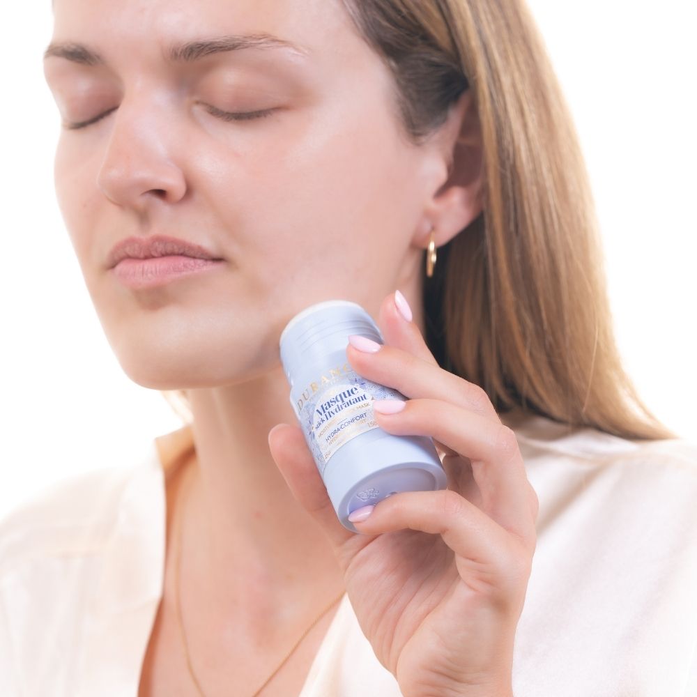 Aplicando la mascarilla hidratante en stick con aceite de borraja Durance en el cuello, con los ojos cerrados en gesto de relax – D'Arome