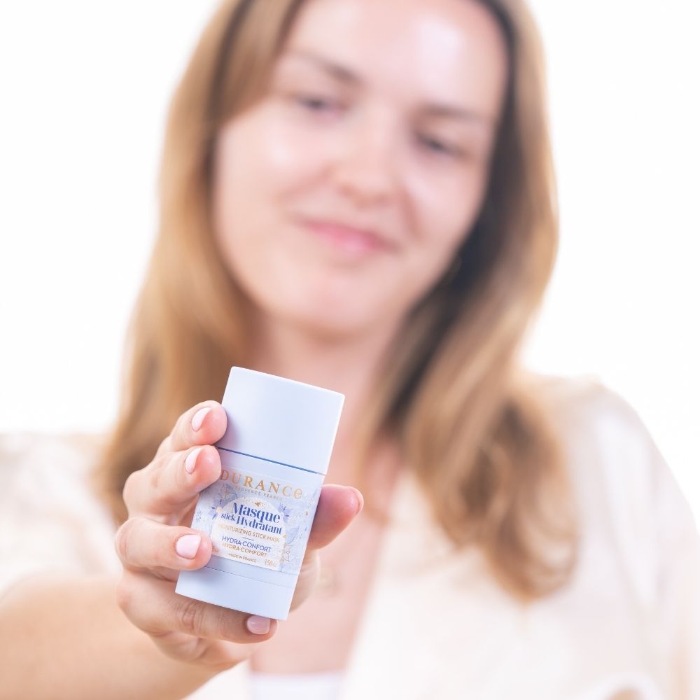 Mostrando la mascarilla hidratante en stick con aceite de borraja Durance sonriente, presentando el producto a cámara – D'Arome