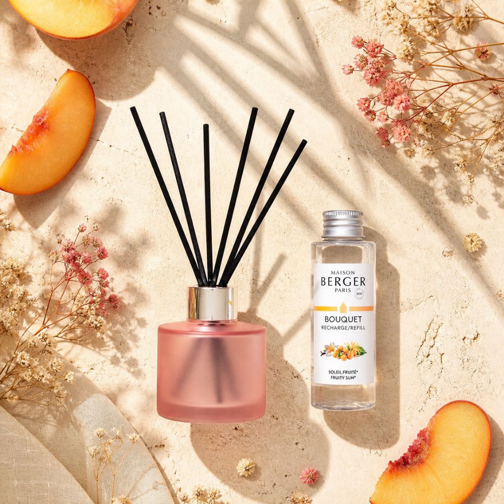 Mini Mikado Rosa Escarchado Maison Berger con recarga Soleil Fruité sobre piedra natural con rodajas de melocotón y flores secas