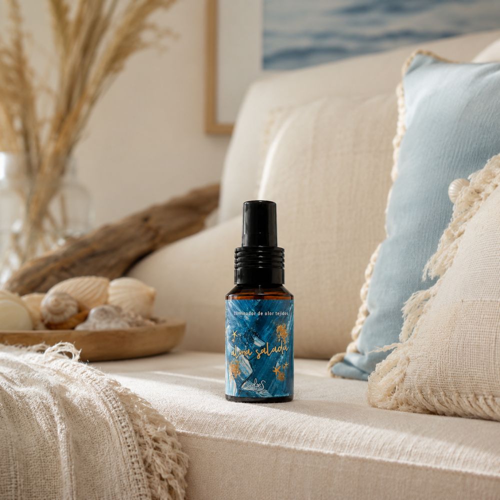 Mini spray textil Alma Salada de LoeS de 50 ml sobre un sofá beige con cojines azules y decoración costera de inspiración mediterránea – D'Arome