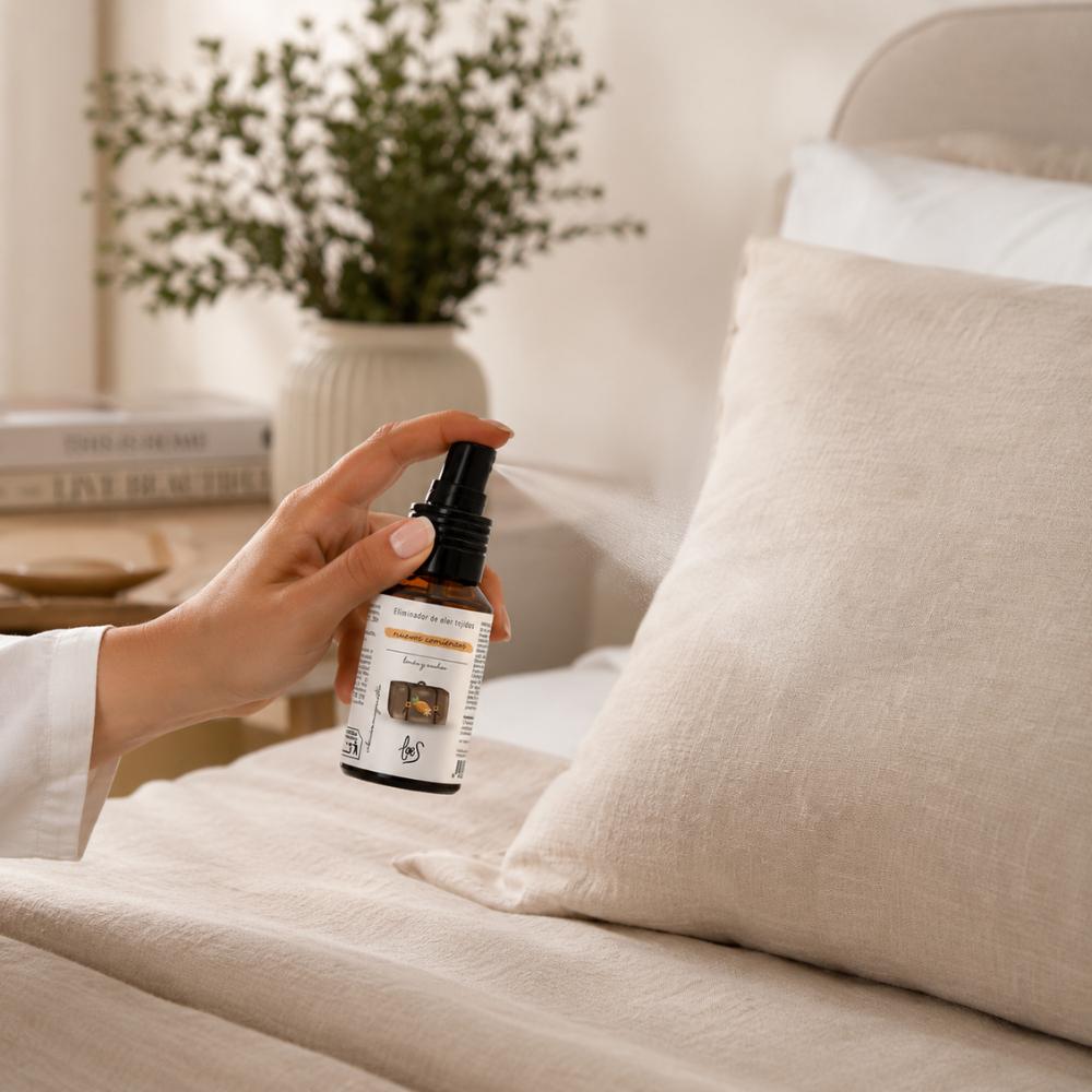 Aplicación del mini spray textil eliminador de olores Nuevos Comienzos 50ml de LoeS sobre almohada de lino en dormitorio, ideal para hotel y viajes – D'Arome