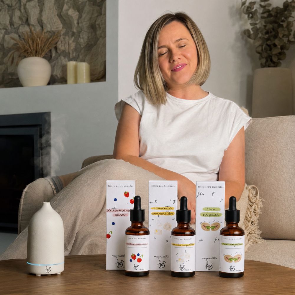 Ana Belén, embajadora de D'Arome, disfrutando del pack de aromas dulces LoeS junto al difusor de cerámica blanca LoeS encendido en el sofá con una taza humeante – D'Arome