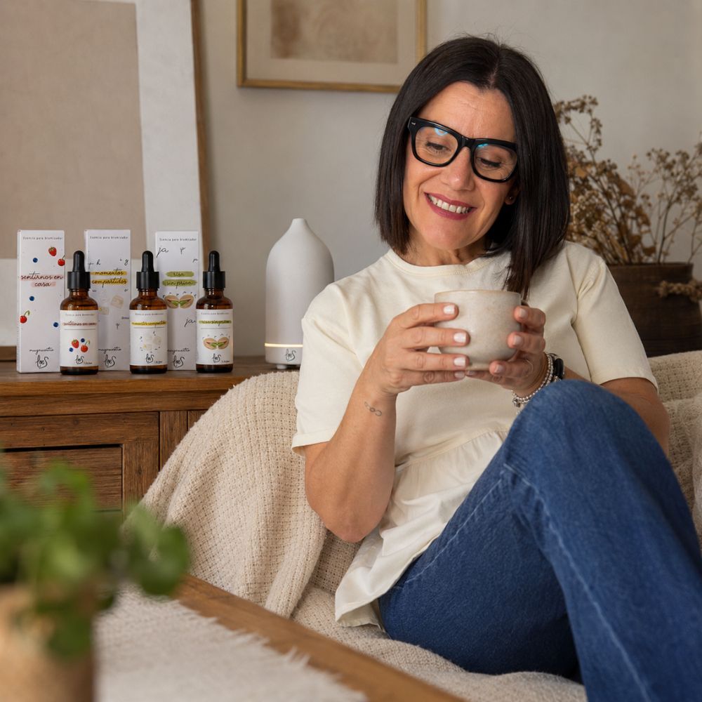 María Carmen, CEO de D'Arome, disfrutando del aroma del pack de aromas dulces LoeS con el difusor de cerámica blanca LoeS encendido en el salón junto a la chimenea – D'Arome