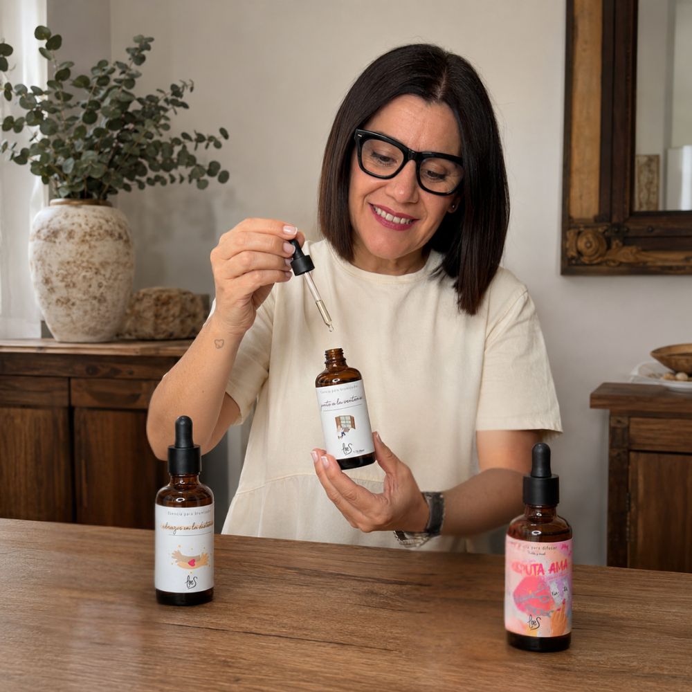 Mari Carmen, CEO y experta en aromas de D'Arome, oliendo el cuentagotas de la esencia Junto a la Ventana del pack de aromas orientales LoeS sobre mesa de madera – D'Arome