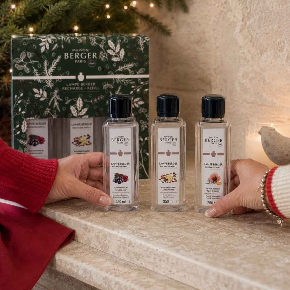 Detalle de manos junto al estuche de regalo navideño Maison Berger con tres recargas de 250 ml – D'Arome