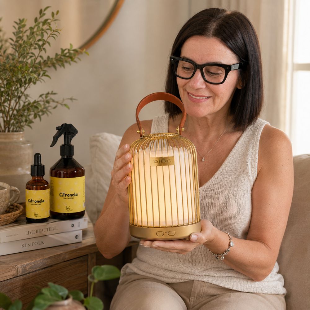 Mujer sosteniendo el difusor inalámbrico farol Esteban dorado encendido con pack citronela LoeS en mesita, ambientador antimosquitos para el hogar – D'Arome
