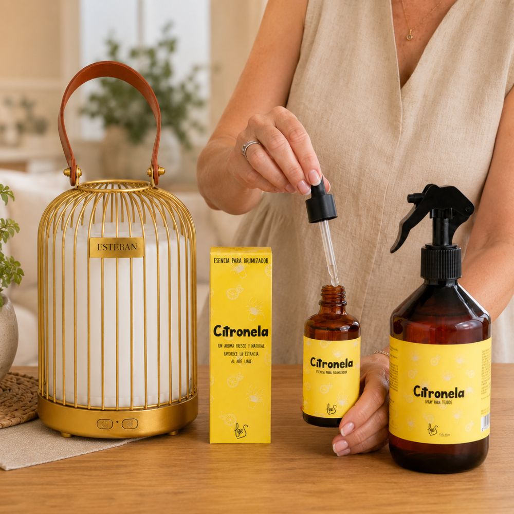 Manos añadiendo esencia de citronela LoeS con cuentagotas al difusor inalámbrico farol Esteban dorado, pack Anti-Mosquitos D'Arome