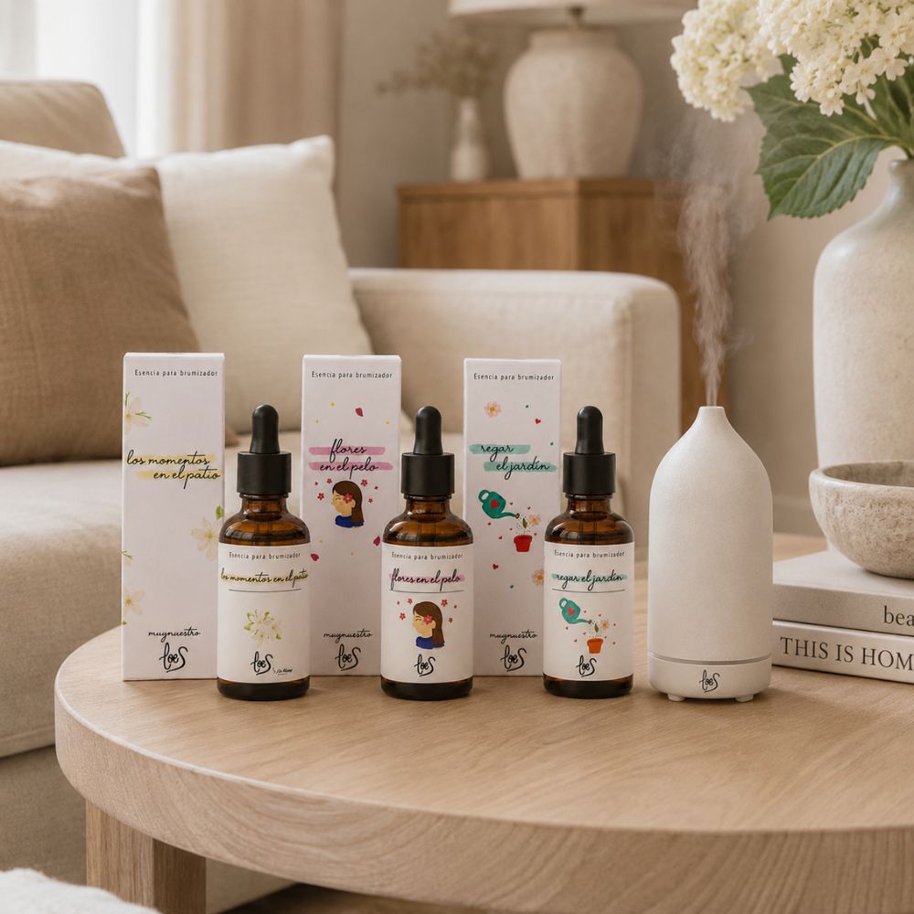 Pack de tres esencias florales para difusor LoeS ambientando un salón nórdico sobre mesa de roble con brumizador cerámico encendido – D'Arome